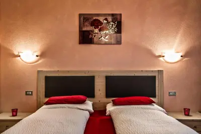 two beds in a room with two red pillows at Ciasa Confolia in Corvara in Badia