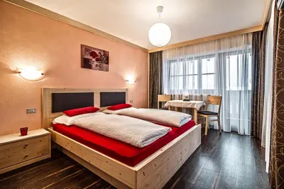 a bedroom with a large bed and a table at Ciasa Confolia in Corvara in Badia