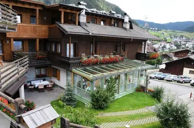 a large wooden house with a courtyard in front of it at Ciasa Confolia in Corvara in Badia
