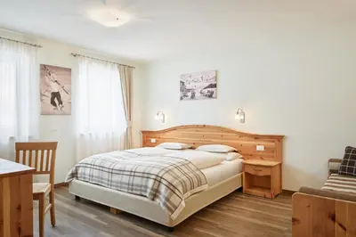 a bedroom with a bed and a table and a chair at Residence Baron in San Vigilio Di Marebbe