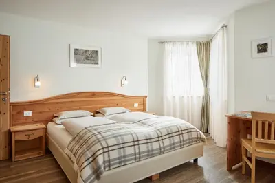 a bedroom with a bed and a desk and a window at Residence Baron in San Vigilio Di Marebbe