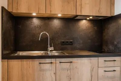 a kitchen with a stainless steel sink and wooden cabinets at Residence Neuhof in Tirolo
