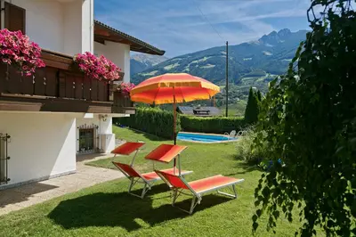 a patio with a table and chairs and an umbrella at Residence Neuhof in Tirolo
