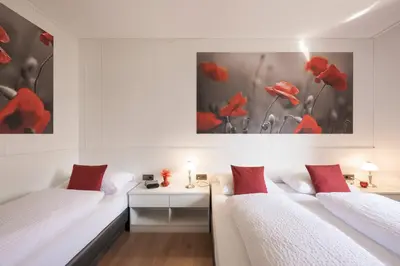 two beds in a room with red flowers on the wall at Residence Neuhof in Tirolo