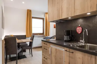 a kitchen with a sink and a table in a room at Residence Neuhof in Tirolo