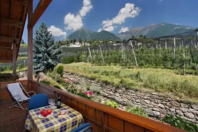a table and chairs on a balcony with a view at Residence Neuhof in Tirolo