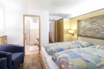 a bedroom with a bed and a chair and a mirror at Apartments Mirandula in Ortisei