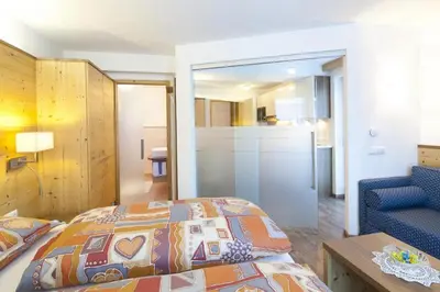 a bedroom with a bed and a blue chair at Apartments Mirandula in Ortisei