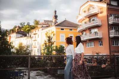 two women standing on a bridge in front of a building at NoveCase Smart Holidays - Gasthof Neunhaeusern in Rasùn di Sotto