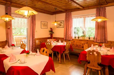 a restaurant with tables and chairs with red table cloth at Pension Talblick in Laion