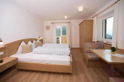 a bedroom with a bed and a desk and a window at Pension Talblick in Laion
