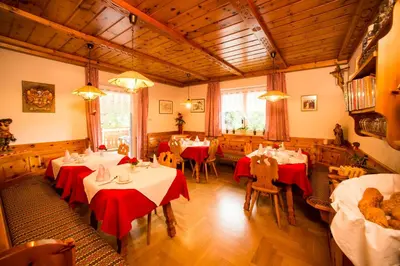 a restaurant with tables and chairs with red table cloth at Pension Talblick in Laion