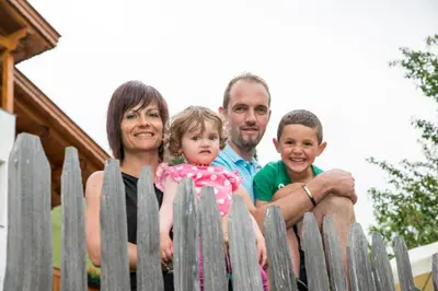 a man and a woman and two children standing behind a fence at Pension Talblick in Laion