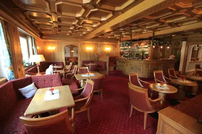 a restaurant with tables and chairs and a bar at Hotel Cesa Tyrol in Canazei