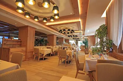 a dining room with tables and chairs in a restaurant at Hotel Cesa Tyrol in Canazei