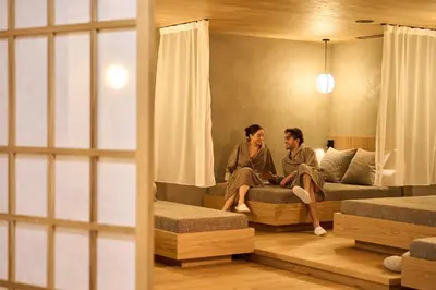 two people sitting on a bed in a room at Hotel Cesa Tyrol in Canazei