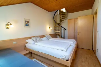 a bedroom with two beds and a spiral staircase at Residence Sporting in Brunico