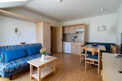 a living room with a blue couch and a kitchen at Residence Sporting in Brunico