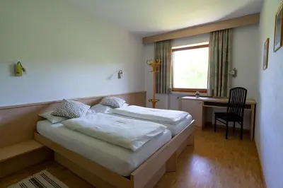 a bedroom with two beds and a desk and a window at Residence Sporting in Brunico