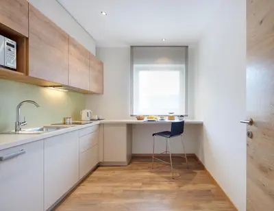 a kitchen with white cabinets and a sink and a chair at Appartments Waage in Bressanone