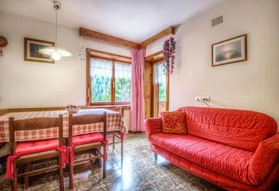 a living room with a red couch and a table at Apartments Fiordalisi in Colfosco
