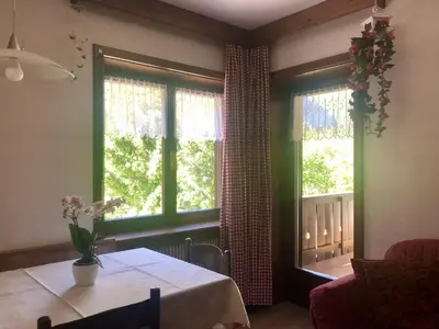 a living room with a table and two windows at Apartments Fiordalisi in Colfosco