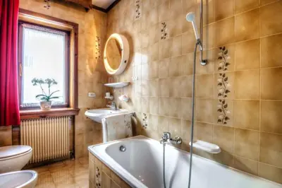 a bathroom with a tub and a toilet and a sink at Apartments Fiordalisi in Colfosco