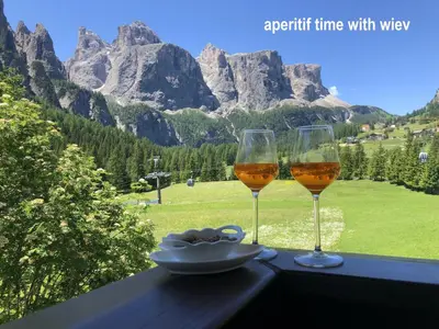 two glasses of wine sitting on a table with mountains at Apartments Fiordalisi in Colfosco