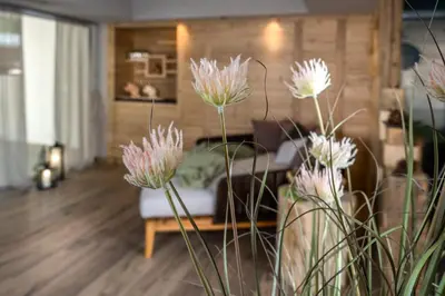 a living room with a couch and pink flowers at Cesa Edelweiss Living & Spa in Campitello di Fassa