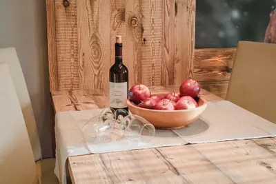 a bottle of wine and a bowl of apples on a table at Cesa Edelweiss Living & Spa in Campitello di Fassa
