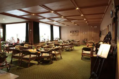 a restaurant with tables and chairs and people sitting at tables at Hotel Alpino Plan in Selva di Val Gardena
