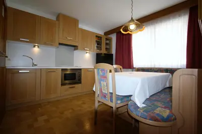 a kitchen with a table and a chair and a sink at Pera Ciaslat in Colfosco