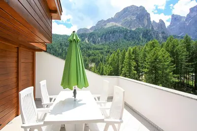 a table and chairs on a balcony with a green umbrella at Pera Ciaslat in Colfosco