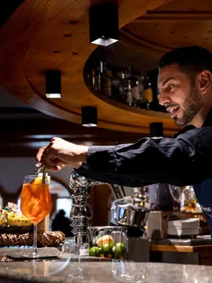 a man is preparing a drink in a bar at Hotel Scoiattolo in Tesero