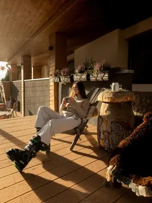 a woman sitting in a chair talking on a cell phone at Hotel Scoiattolo in Tesero
