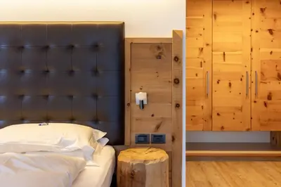 a bedroom with a bed with a black headboard and a table at Hotel Scoiattolo in Tesero