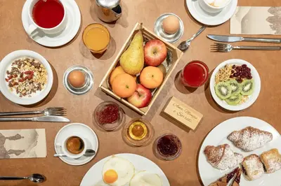 a table topped with plates and bowls of food and fruit at Hotel Scoiattolo in Tesero