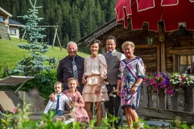 a family posing for a picture in front of a cabin at Hotel Welponer in Selva di Val Gardena