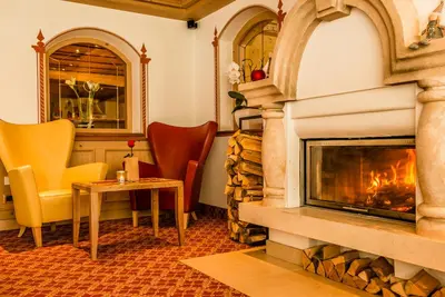 a fireplace in a room with chairs and a table at Hotel Welponer in Selva di Val Gardena