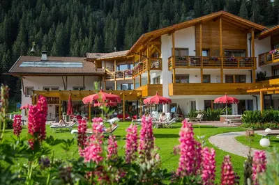 a hotel with red umbrellas in a field of flowers at Hotel Welponer in Selva di Val Gardena
