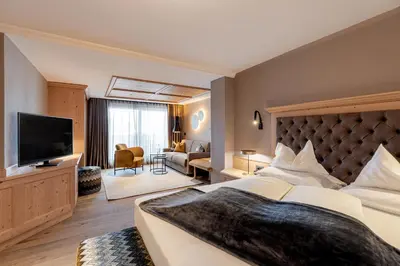 a bedroom with a large bed and a living room at Hotel Welponer in Selva di Val Gardena