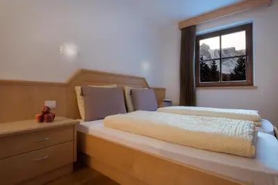 a bedroom with a large bed with a window at Appartamenti Villa Olympia in Corvara in Badia