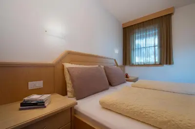 a small bedroom with a bed and a window at Appartamenti Villa Olympia in Corvara in Badia