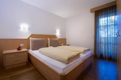 a bedroom with a large bed and a window at Appartamenti Villa Olympia in Corvara in Badia