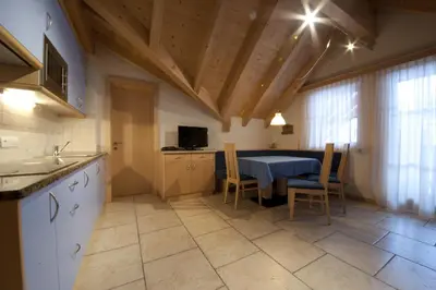 a kitchen with a table and chairs in a room at Appartamenti Villa Olympia in Corvara in Badia