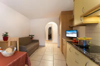 a kitchen and living room with a couch and a table at Appartamenti Villa Olympia in Corvara in Badia