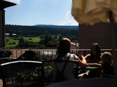 a group of women sitting on a balcony looking out at a mountain at Garni Le Maddalene in Coredo