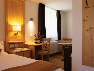 a hotel room with a bed and a desk and a window at Garni Le Maddalene in Coredo