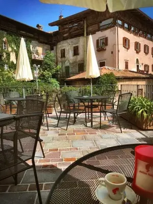 an outdoor patio with tables and chairs and umbrellas at Garni Le Maddalene in Coredo