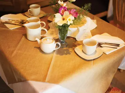 a table with cups and a vase of flowers on it at Garni Le Maddalene in Coredo